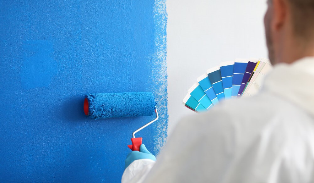 craftsman holds color pallet and paints wall